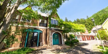A traditional building with a green door, a balcony, and a small garden area.