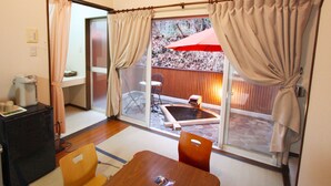 A compact room with a television, a small refrigerator, a dining table with chairs, and a sliding glass door leading to an outdoor area with a hot tub and a red umbrella. - Hotel Euro City (Nikko)