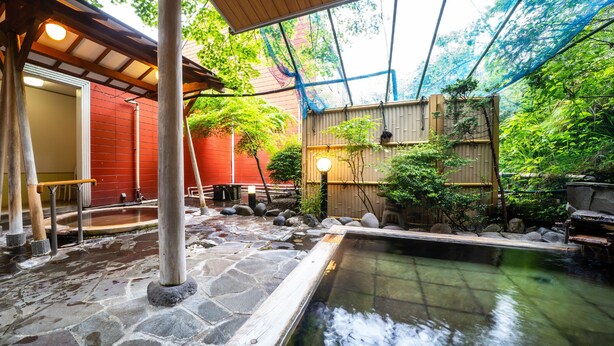 A traditional Japanese onsen with stone flooring, a wooden bath, and a covered seating area. - Hotel Euro City (Nikko)
