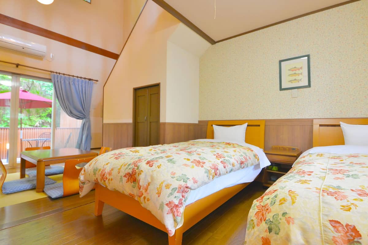 A hotel room with two beds, a wooden table, and a chair.