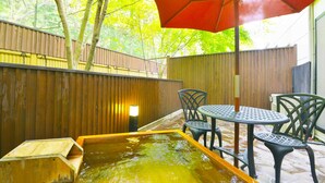 A wooden deck with a hot tub, a table with chairs, and an umbrella. - Hotel Euro City (Nikko)