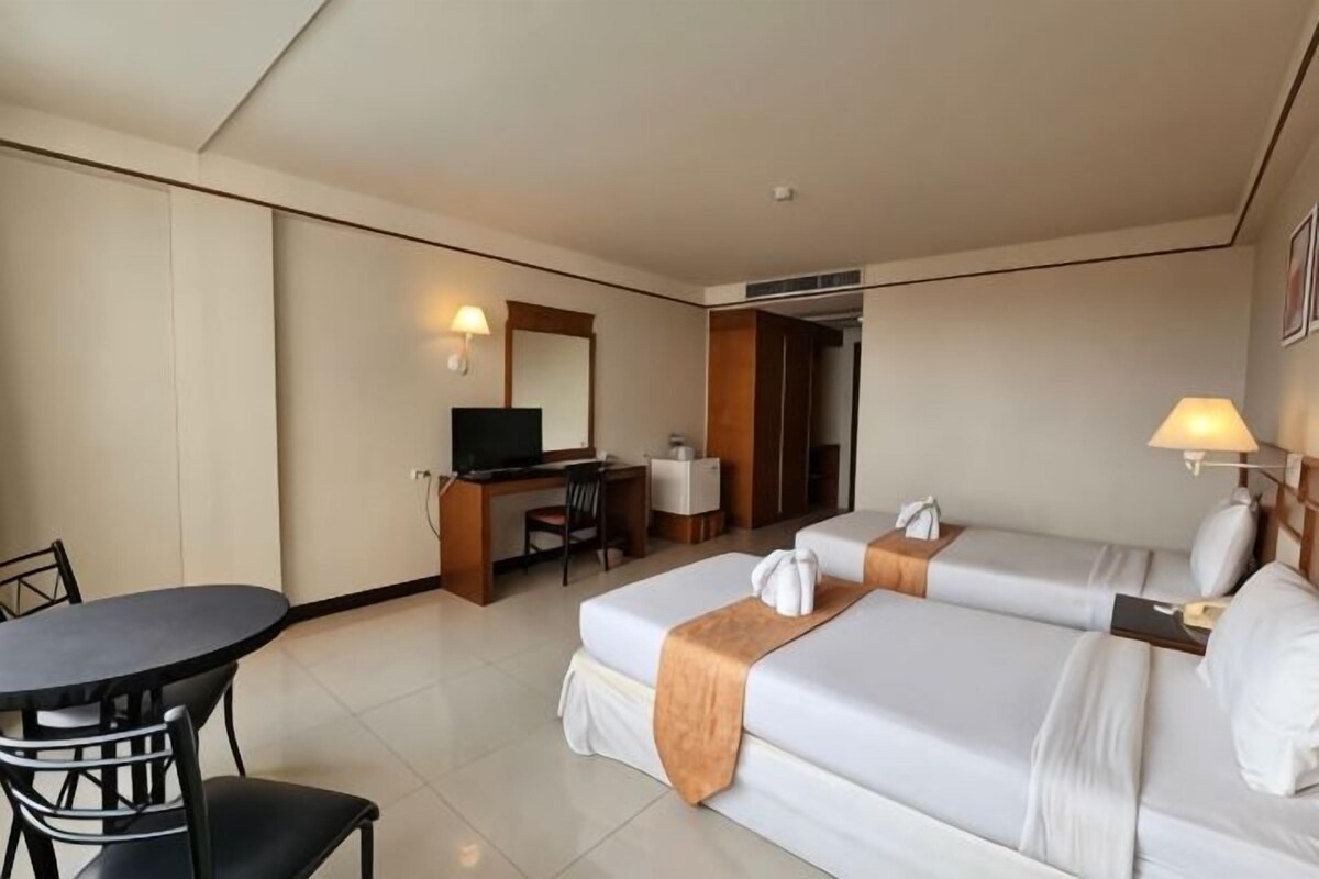 A hotel room with a bed, desk, chair, and a television.