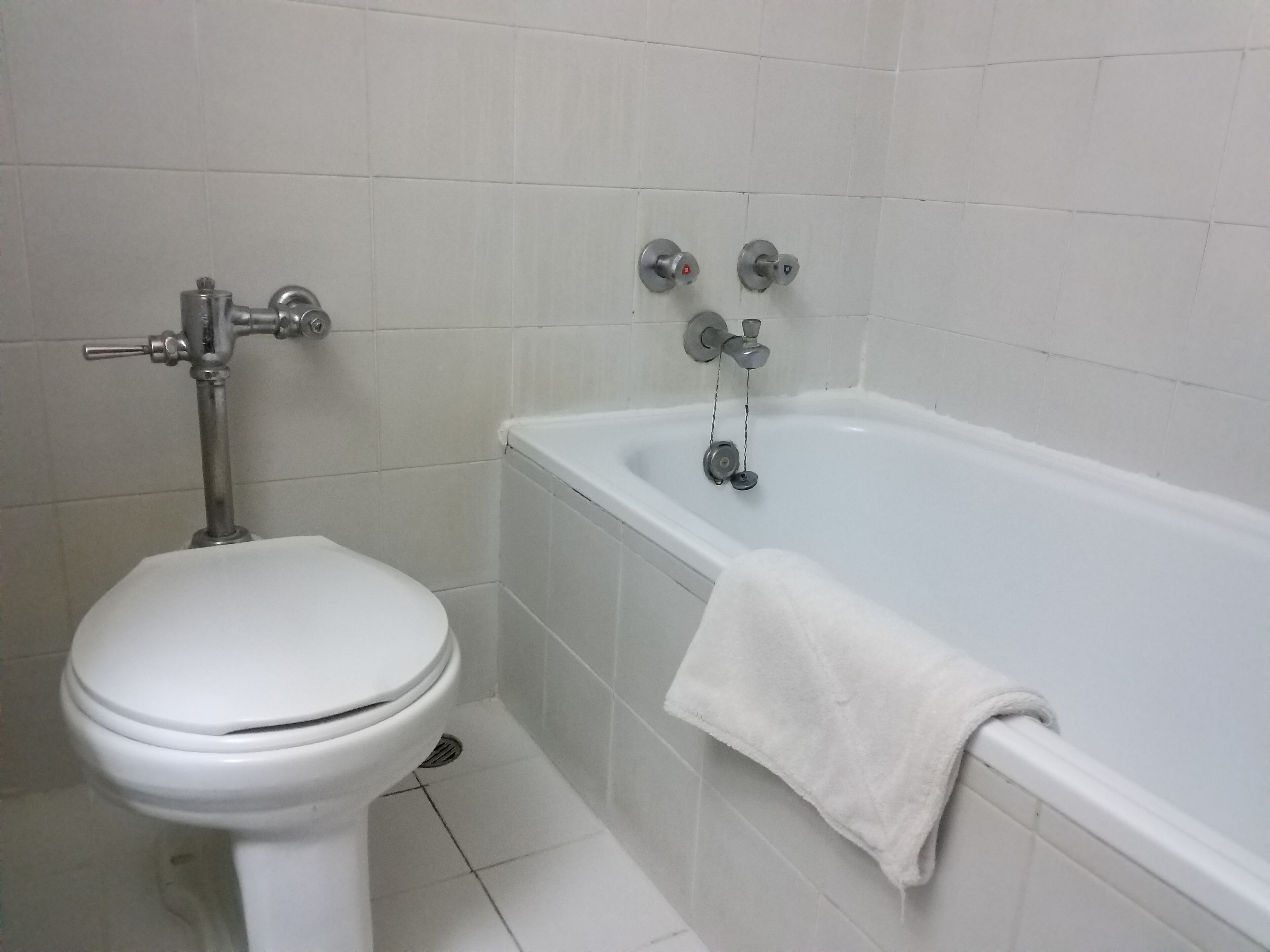 Un baño con inodoro blanco, bañera con toalla blanca y ducha.