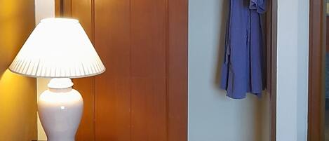 A wooden door with a sign, a lamp, and a robe hanging on a rack in a room.