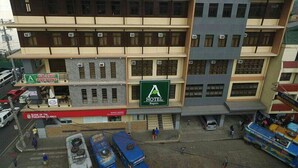 A multi-story building with a green sign for a hotel and a red sign for a bank. - A Hotel Baguio (Baguio)