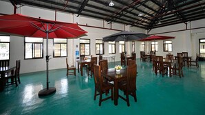 A spacious indoor dining area with wooden tables and chairs, red umbrellas, and large windows allowing natural light. - A Hotel Baguio (Baguio)
