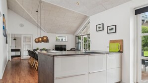 A modern kitchen with a large island, white cabinetry, and a dining area with a bench and chairs. - Gorgeous home in Grenaa with sauna (Grenaa)