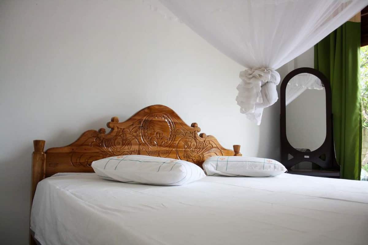 A bed with a wooden headboard, white bedding, and a canopy.