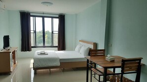 Une chambre à coucher comprenant un lit, un bureau, une chaise, un téléviseur et une fenêtre avec des rideaux.