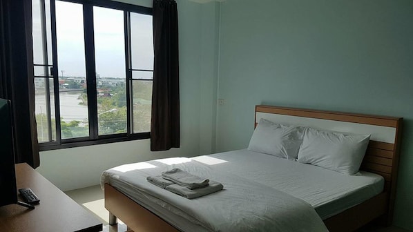 Ein Schlafzimmer mit Bett, Fenster und Schreibtisch.