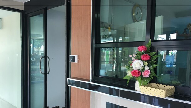 Un espace d’accueil moderne doté d’une porte en verre, d’un panneau en bois et d’un comptoir noir.