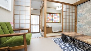 Ein traditioneller japanischer Raum mit Tatami-Bodenbelag, einem grünen Sofa, einem Holztisch und Shoji-Schirmwänden.