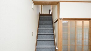 Eine Treppe mit Teppichstufen und einem Holnändergeländer, die zu einem Raum mit einer Holztür und Milchglasscheiben führt.