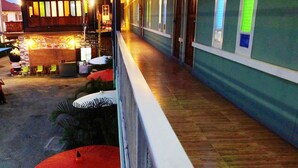 A hotel corridor with a bar area on the left, wooden flooring, and a green wall with vertical light strips.
