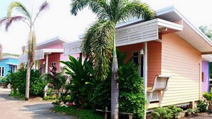 A row of colorful, single-story houses with a paved walkway in front.