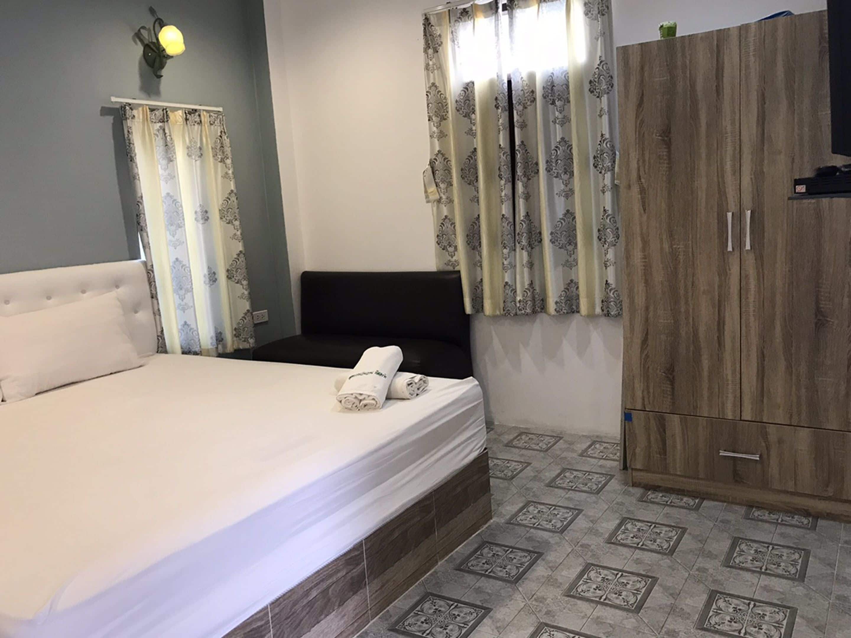 Ein Schlafzimmer mit Bett, Kleiderschrank und Vorhängen.