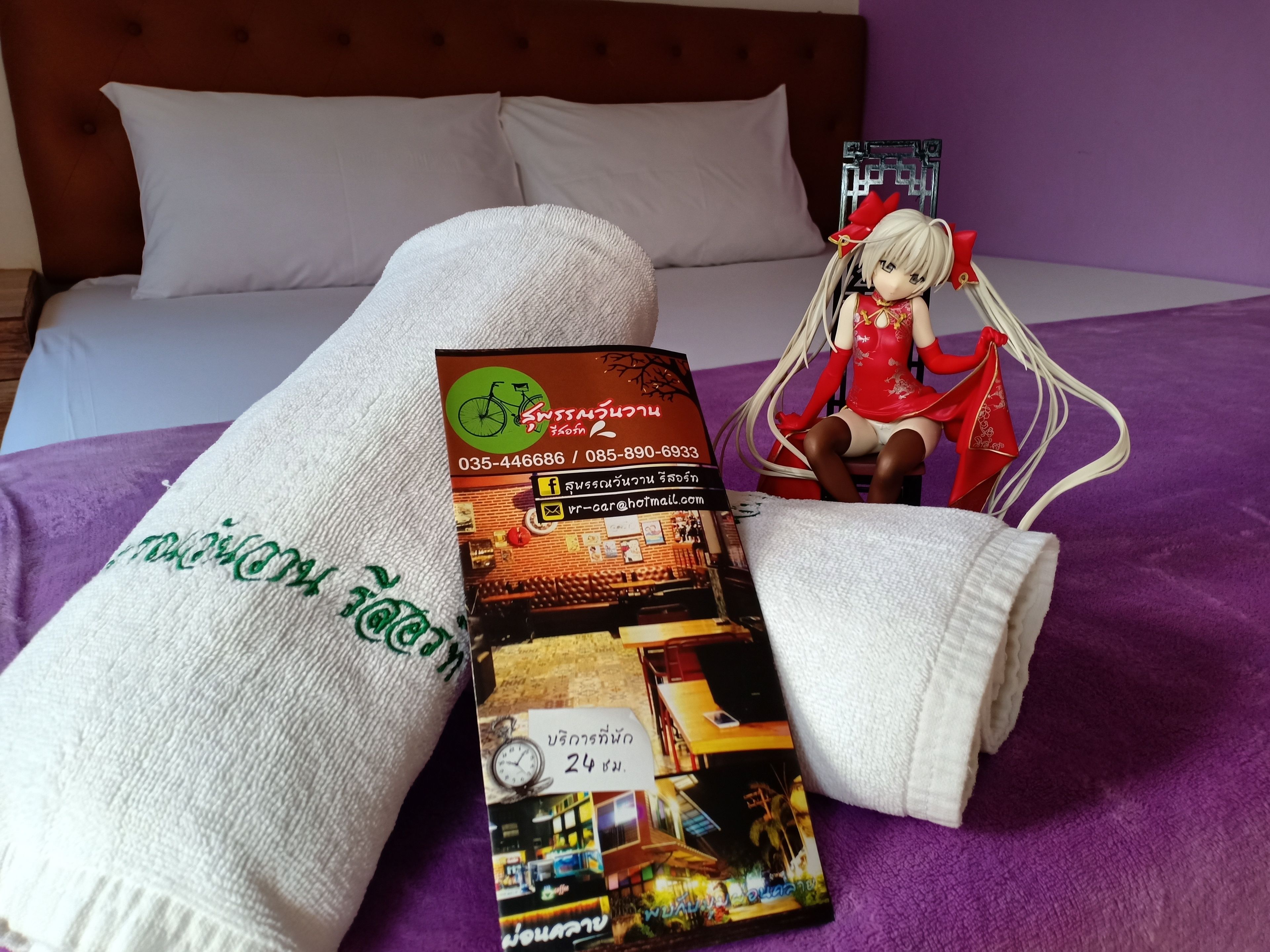 A bed with a white blanket and a brochure on it.