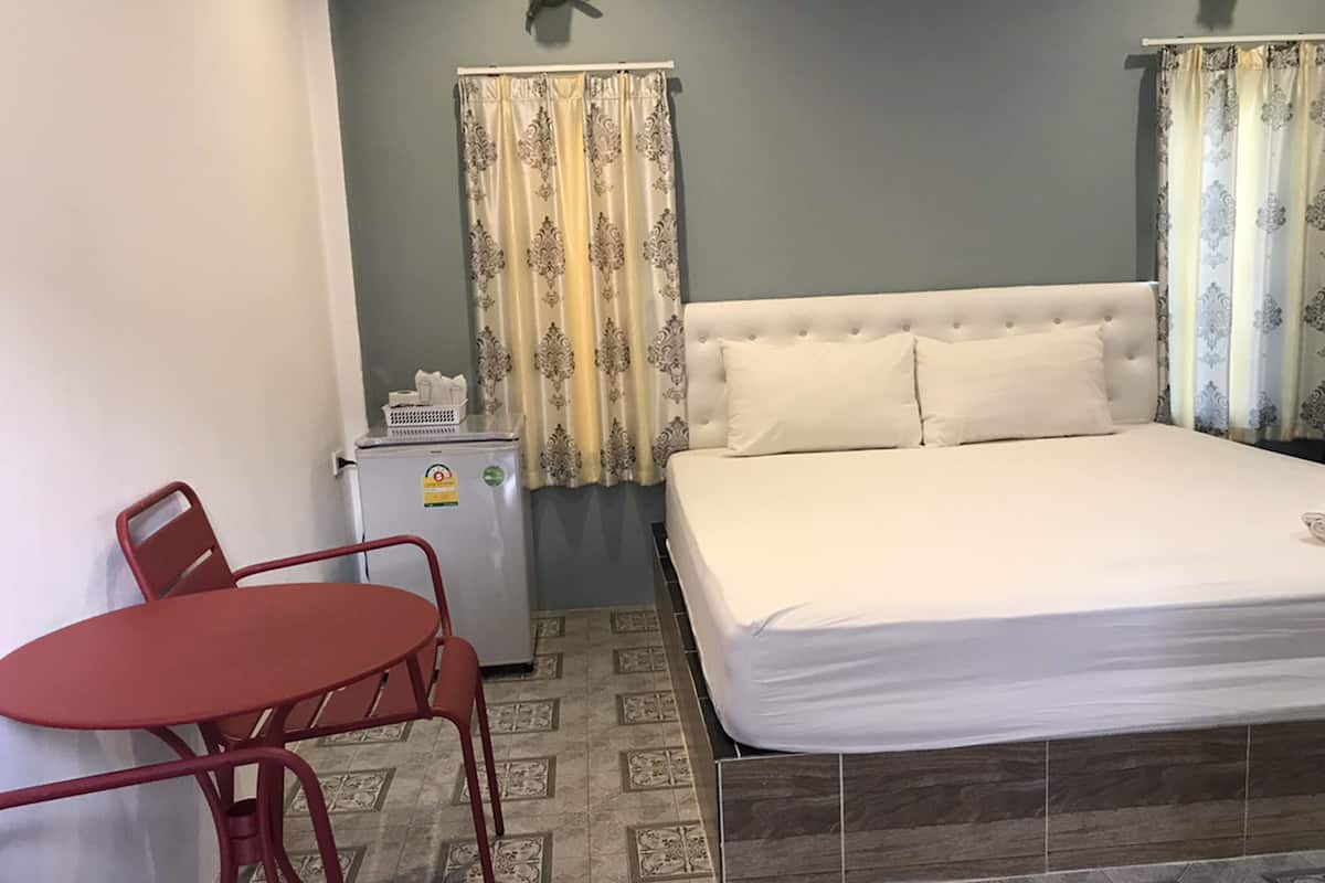 Une chambre à coucher avec un lit, une petite table et un réfrigérateur.