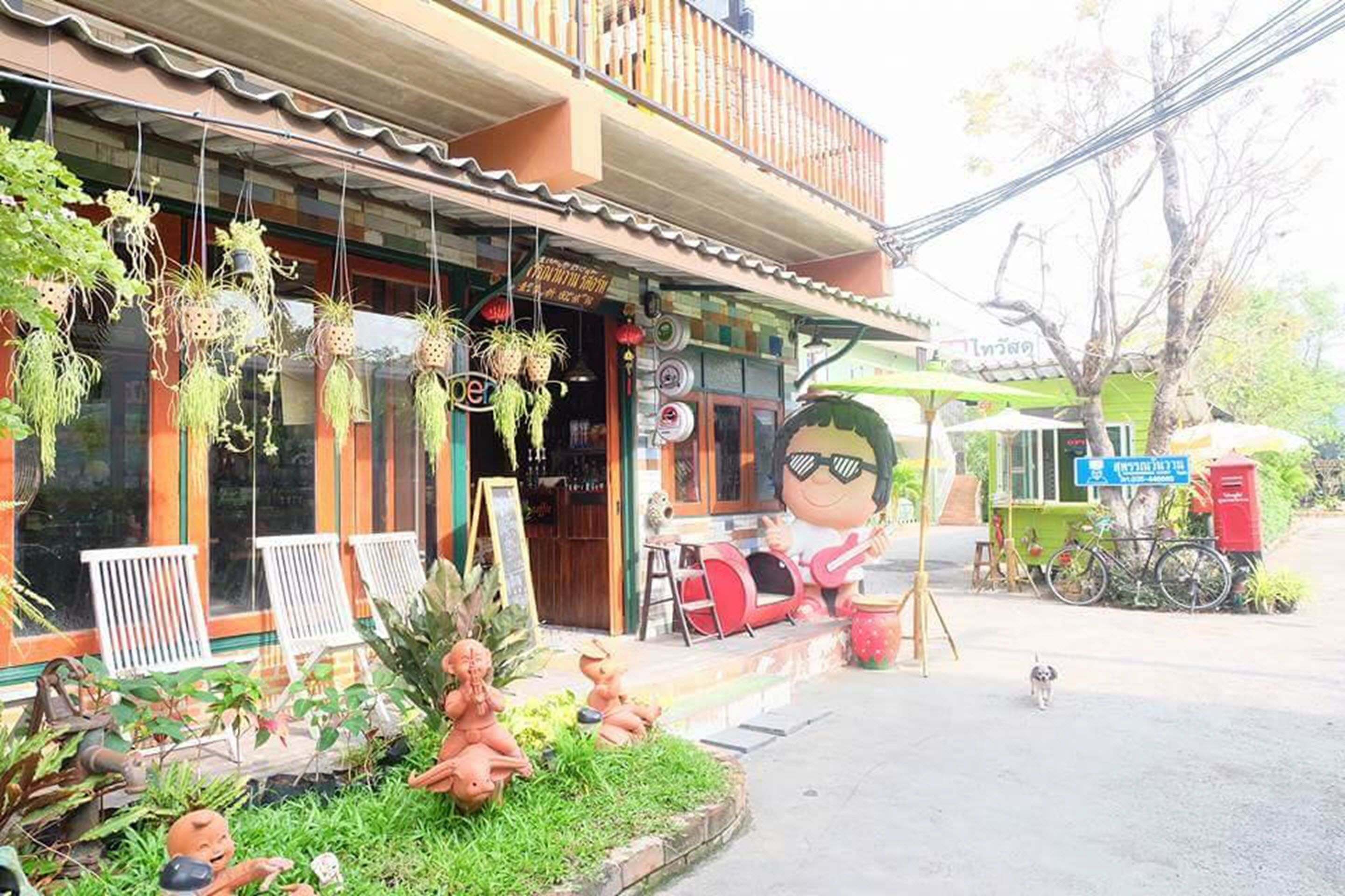 Un restaurante con mesas al aire libre, plantas colgantes y una decoración con un personaje de dibujos animados.