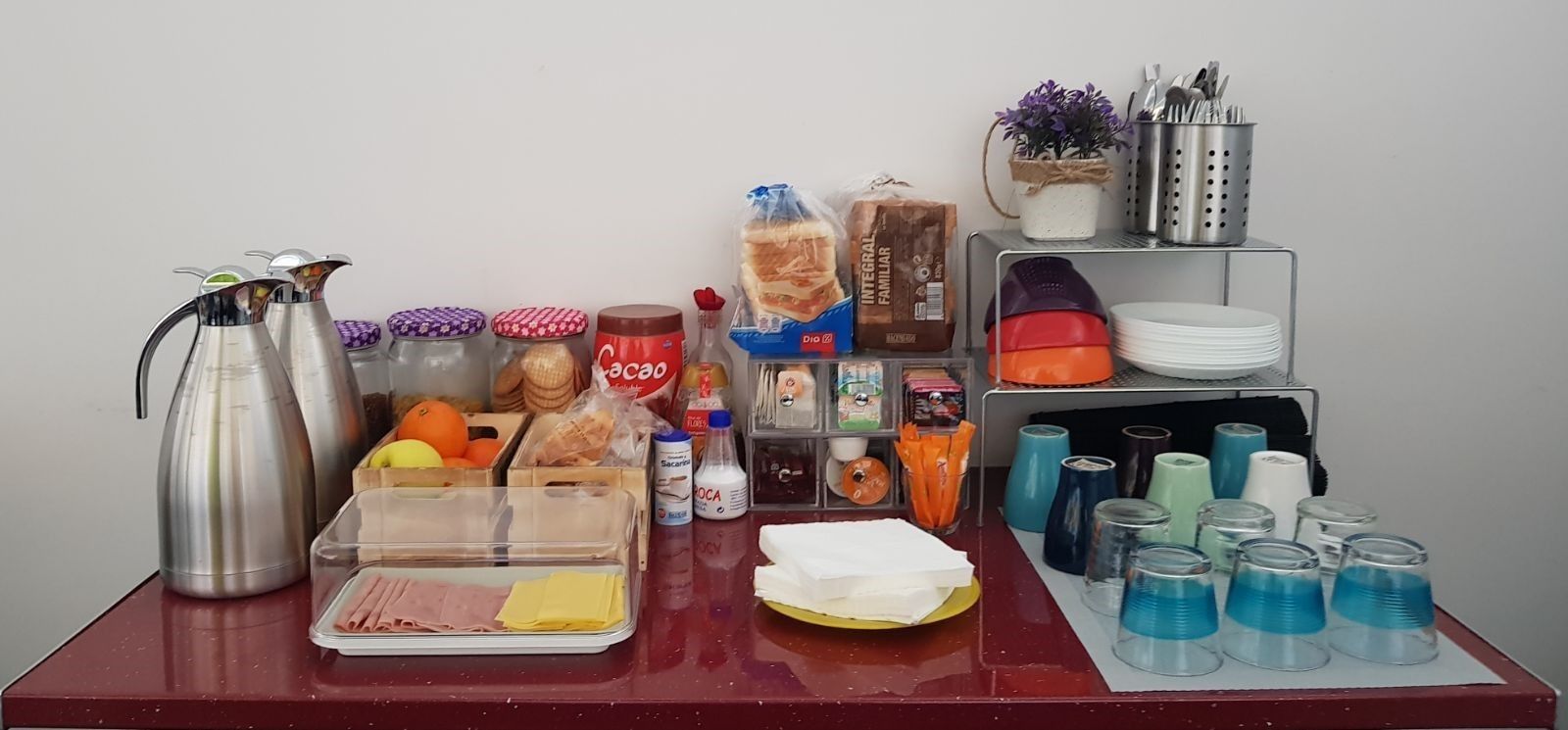Una mesa de buffet con diferentes alimentos, bebidas y utensilios.