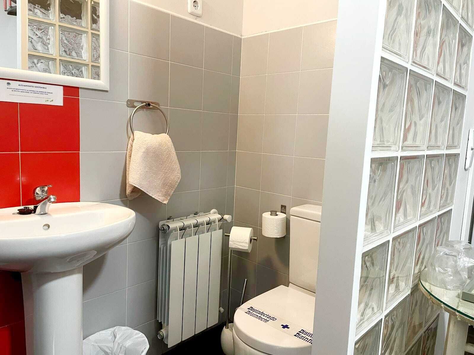 A bathroom with a white sink, a towel rack, a toilet, and a glass shower enclosure.