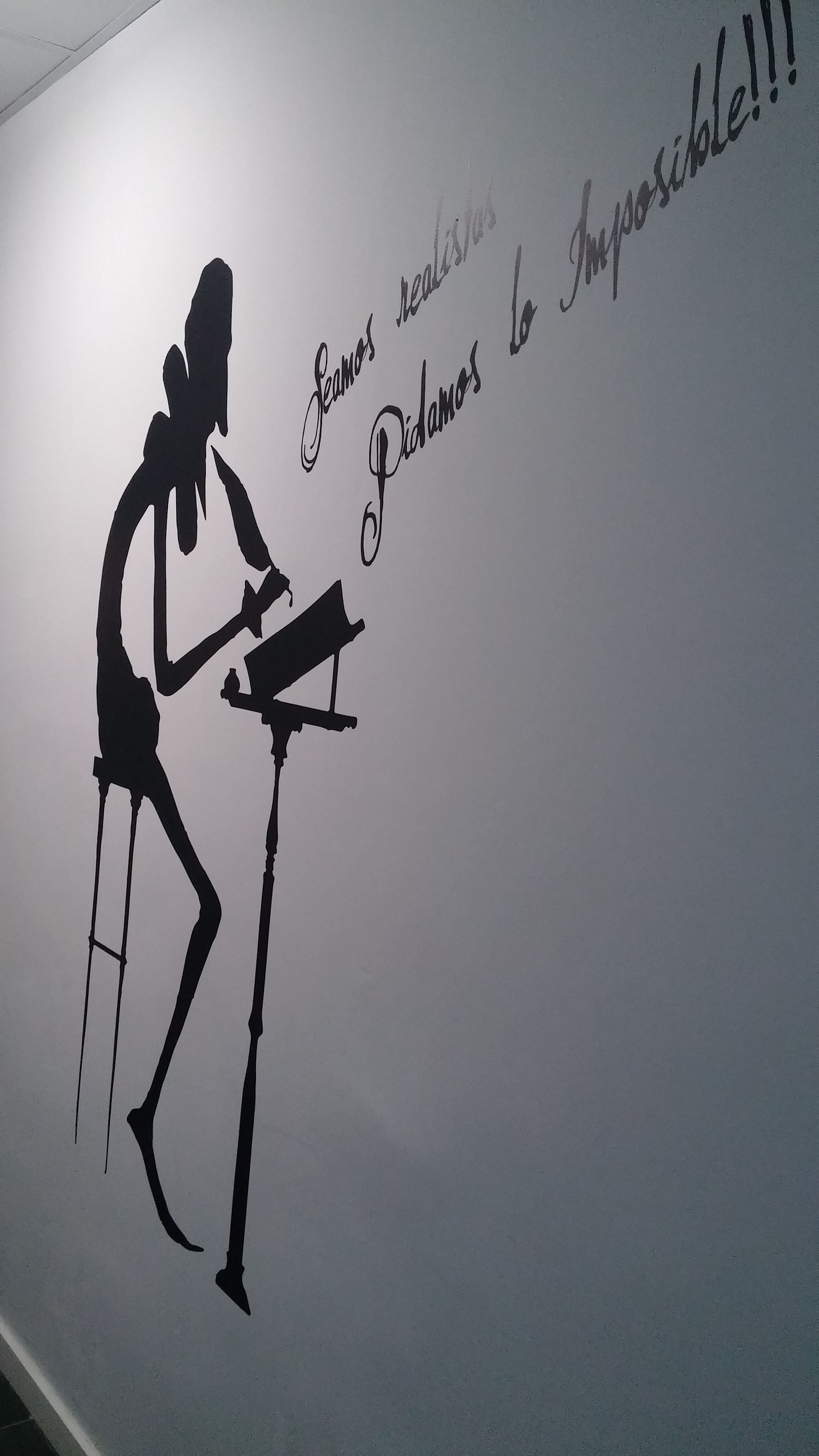 A silhouette of a person playing a piano against a wall with text in Spanish.