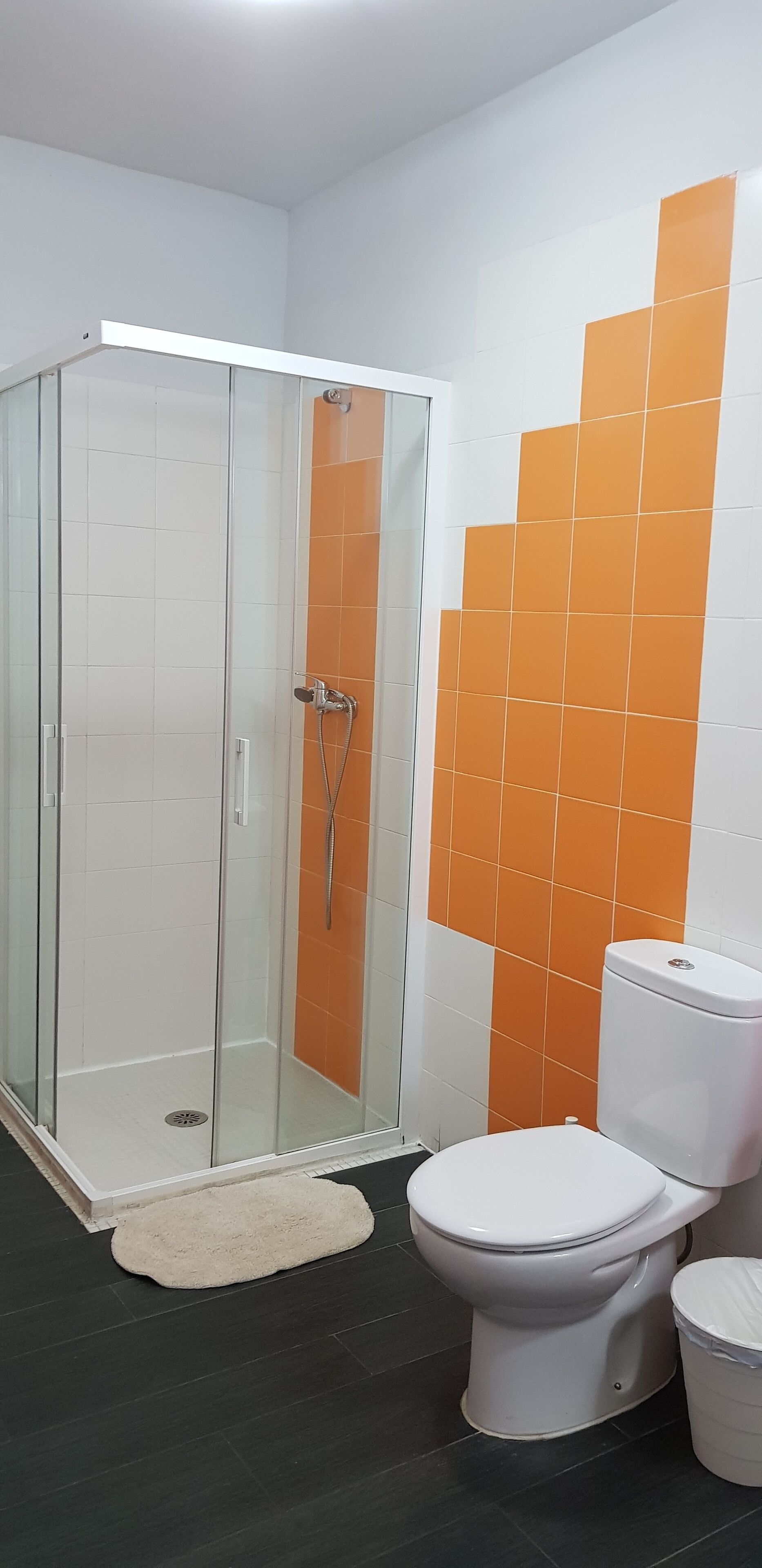 Un baño con ducha de vidrio, inodoro y lavamanos.