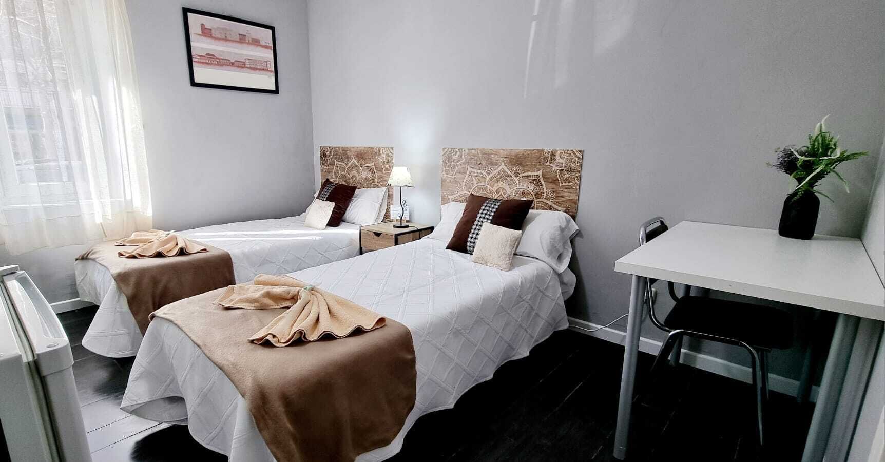 Ein Hotelzimmer mit zwei Betten, einem Schreibtisch und einem Stuhl.