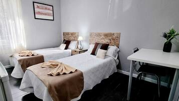 Ein Hotelzimmer mit zwei Betten, einem Schreibtisch und einem Stuhl.