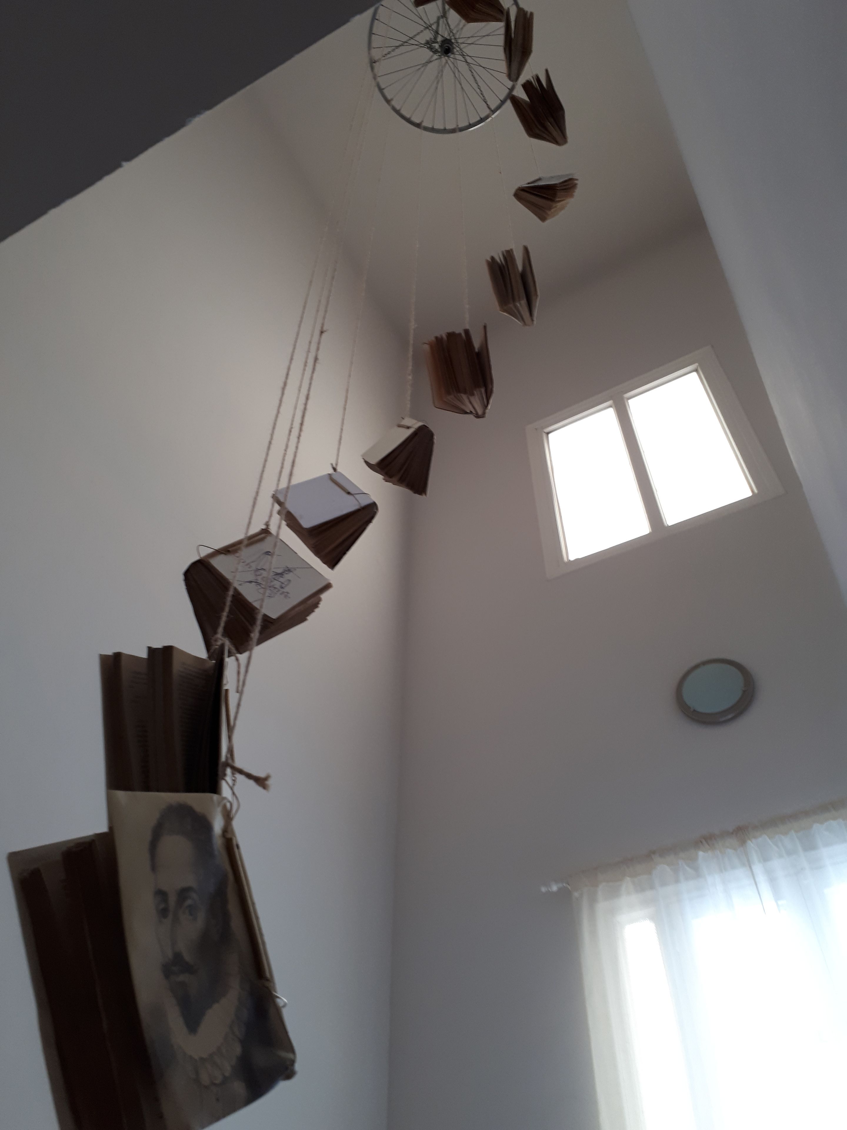Una habitación con techo alto, ventana y ventilador de techo.