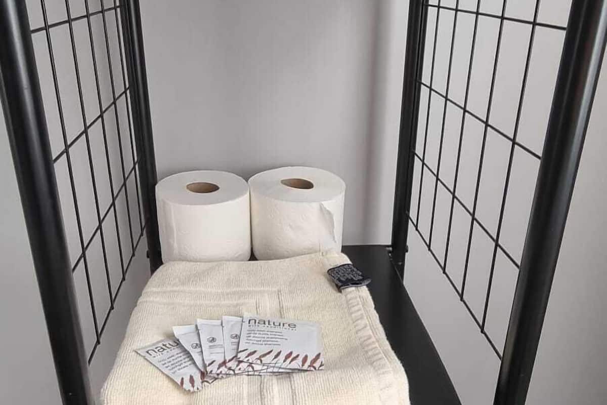 A bunk bed with two rolls of toilet paper, a blanket, and a pink towel.