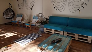 A modern living room with a blue sofa, wooden floor, hanging light fixtures, and a hanging chair. - El Sueño del Quijote (Alcala de Henares)