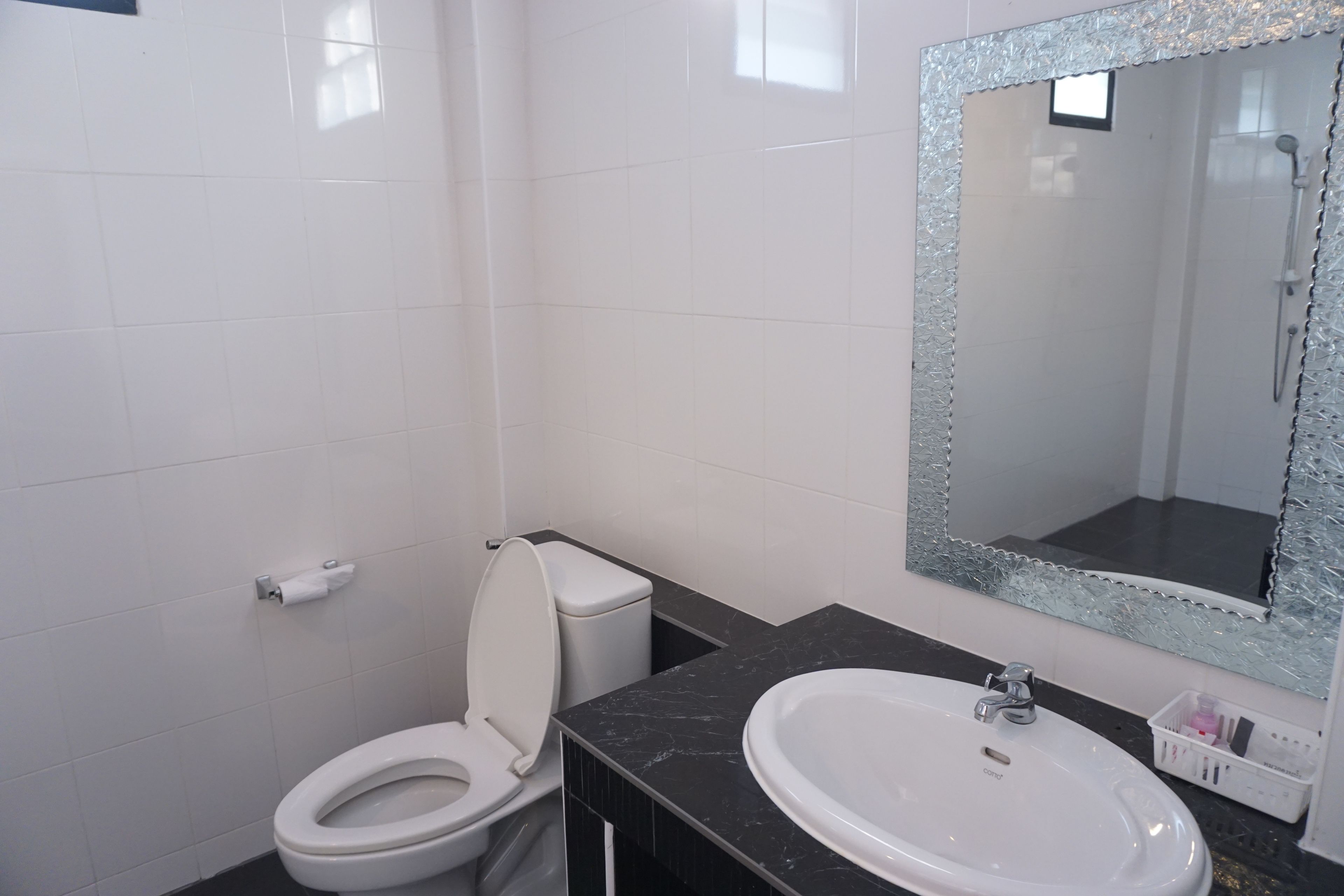 A bathroom with a toilet, sink, and mirror.
