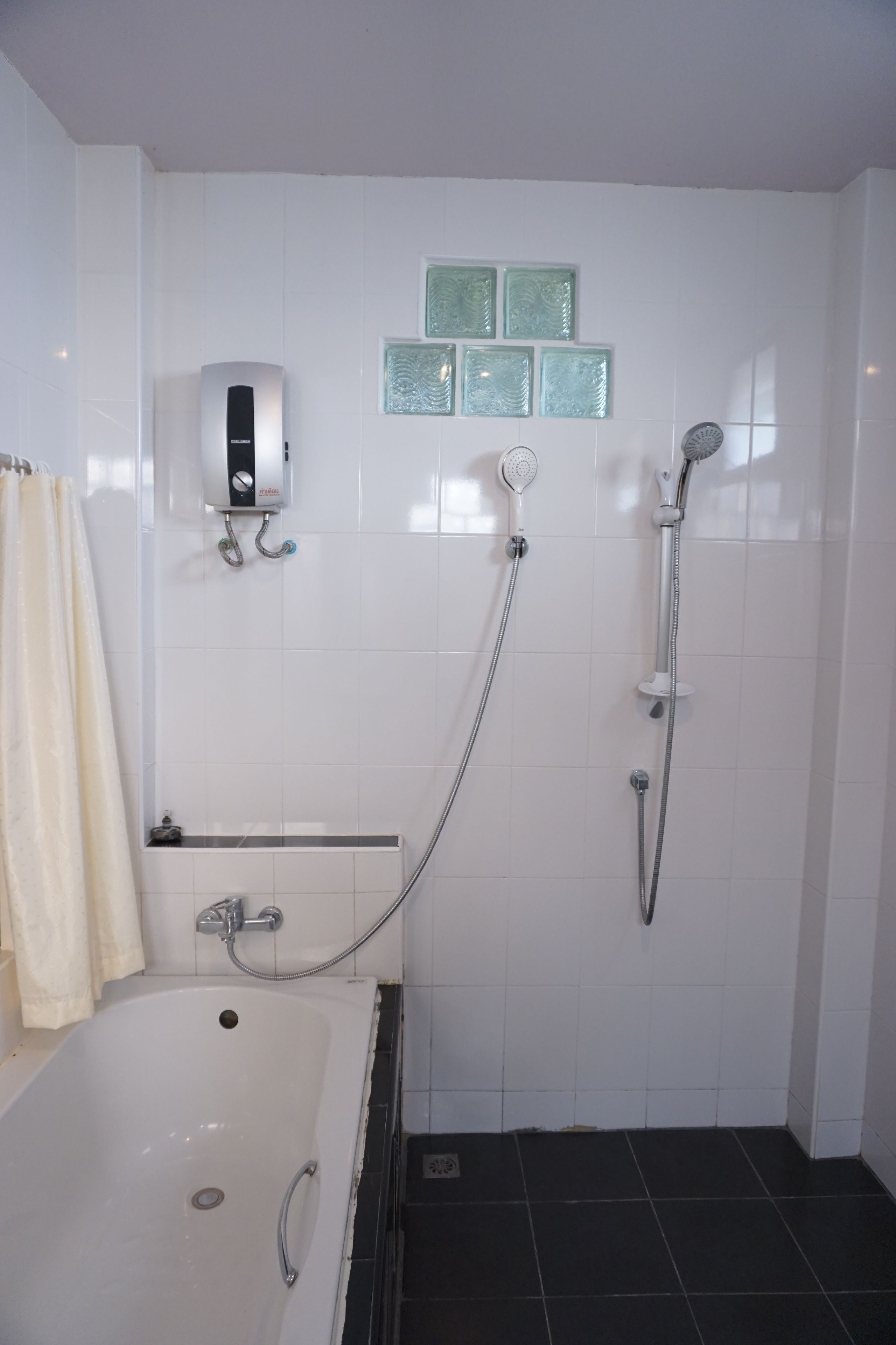 Un bagno con una vasca, una doccia e un asciugamani a muro.