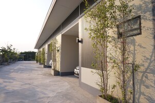 Un edificio moderno con un paseo techado, plantas en macetas y un coche estacionado.
