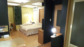 A hotel room with a bed, bedside table, lamp, and a television.