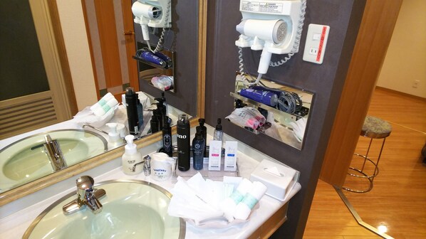 A bathroom with a sink, mirror, and various toiletries.