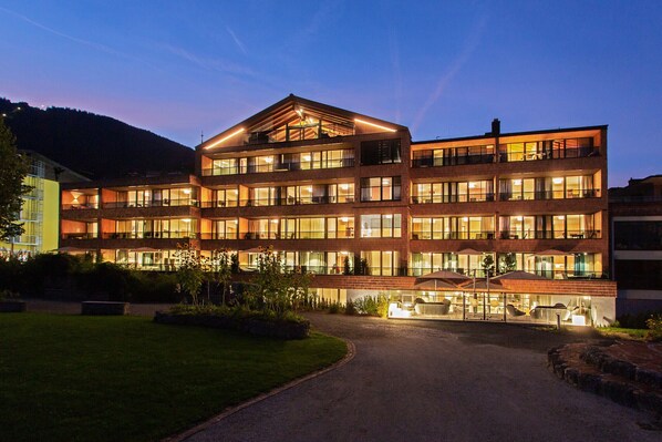 Un hotel de varios pisos con un atrio central, amplias ventanas y una entrada bien iluminada.