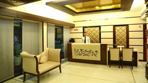 A reception area with a sofa, a reception desk, and a view through a glass door. - Hotel Park Inn (Chandigarh)