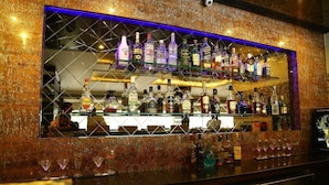 A bar with shelves of liquor bottles and glasses. - Hotel Park Inn (Chandigarh)