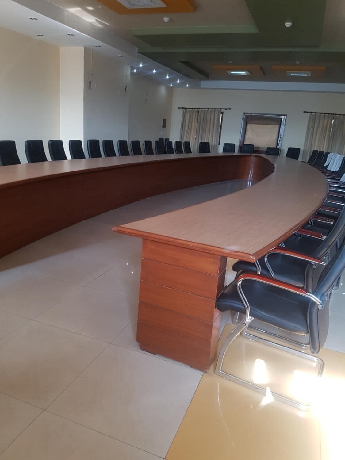 A conference room with a long wooden table and black chairs.