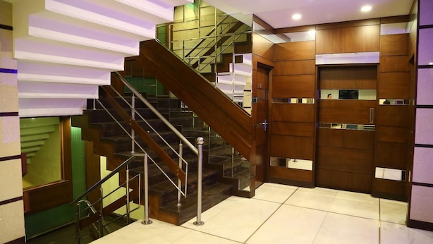 A modern staircase with glass railings and wooden paneling, leading to a lower level. - Hotel Park Inn (Chandigarh)