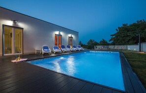 A modern outdoor swimming pool area with lounge chairs and a wooden deck. - Lovely home in Marici with sauna (Marici)