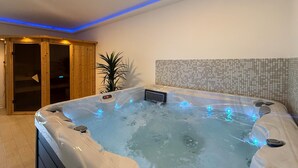A hot tub with a control panel and bubble lights, surrounded by a tiled wall and a wooden door. - Lovely home in Marici with sauna (Marici)