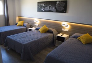 Habitación de hotel con tres camas, cada una con cabecero y mesitas de noche.