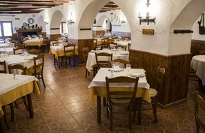 Un restaurante con varias mesas y sillas, paredes de madera y piso de baldosas.