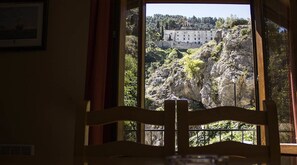 A room with a view of a castle on a hill, a chair in the foreground, and a framed picture on the wall. - Restaurante Pensión Mariola (Agres)
