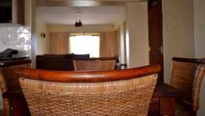 Un comedor con sillas de mimbre y una mesa de madera, un ventilador de techo y vistas a una ventana con cortinas.