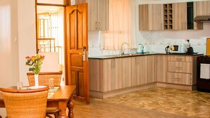 Una cocina con armarios de madera, una mesa de comedor con sillas y un florero con flores.