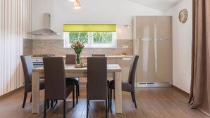 A modern kitchen with a dining table, chairs, a window with a green blind, and a refrigerator. - Awesome home in Vodnjan (Vodnjan)